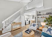 Thumbnail 1 of 64 - A living room with a staircase and a dining area.at Lofts of Wilmington, North Carolina, 28405