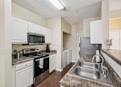 Thumbnail 5 of 32 - A kitchen with a black oven and white cabinets. at Cedar Springs Apartments, North Carolina, 27609