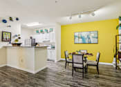 Thumbnail 9 of 36 - Open kitchen and dining area with yellow accent wall at The Arbor Walk Apartments, Tampa, FL 33617