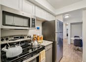 Thumbnail 10 of 62 - A kitchen with a black stove top and a silver refrigerator.