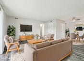 Thumbnail 13 of 45 - A living room with a brown sofa, wooden chairs, and a TV on the wall. at Spyglass Creek, Denver, 80224