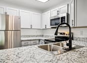 Thumbnail 9 of 55 - A kitchen with a stainless steel refrigerator, microwave, and a granite countertop. at Lakeside Glen Apartments, Florida