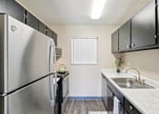 Thumbnail 7 of 35 - A kitchen with a stainless steel refrigerator and black cabinets. at Broadmoor Springs, Colorado Springs, CO
