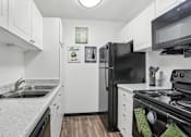 Thumbnail 19 of 57 - A black refrigerator sits in a kitchen with white cabinets. at Millennium at Creve Coeur, Missouri