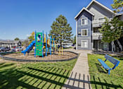 Thumbnail 38 of 44 - A playground with a blue slide and a green slide in the foreground with a building in the background. at Windmill Apartments, Colorado, 80916