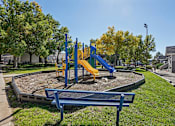Thumbnail 36 of 44 - A playground with a blue bench and a yellow slide. at Windmill Apartments, Colorado Springs, CO
