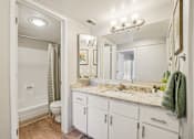 Thumbnail 22 of 62 - A bathroom with a marble countertop and white cabinets.