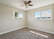 Thumbnail 19 of 56 - A room with a ceiling fan and two windows.at Aspen Townhomes, Colorado Springs, Colorado