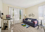 Thumbnail 10 of 32 - A living room with a couch, a table, and a bicycle on the wall. at Cedar Springs Apartments, Raleigh, NC