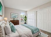 Thumbnail 15 of 55 - A bedroom with a bed, pillows, a nightstand, a lamp, a plant, and a painting on the wall. at Lakeside Glen Apartments, Melbourne, FL