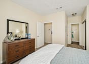 Thumbnail 9 of 32 - A bedroom with a bed, dresser, mirror, and two doors. at Cedar Springs Apartments, North Carolina, 27609
