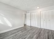 Thumbnail 19 of 45 - A room with white walls and wood flooring with three white closet doors at Spyglass Creek, Denver, 80224