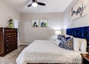 Thumbnail 11 of 105 - A bedroom with a bed, dresser, and two pictures on the wall at Sweetwater At Metro North Apartments, Phoenix  85029