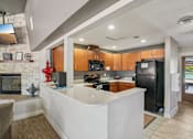 Thumbnail 18 of 35 - A modern kitchen with a white island and wooden cabinets. at University Village Apartments, Colorado