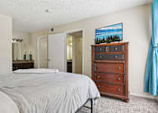 Thumbnail 10 of 39 - A bedroom with a bed, dresser, and mirror.