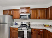 Thumbnail 7 of 70 - A kitchen with a stove, refrigerator, and cabinets. at Heritage at the River, Manchester, 03102