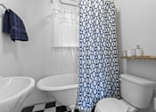 Thumbnail 8 of 34 - A white toilet sits next to a white sink in a bathroom with a blue and white shower curtain.at The Collection of Historic Richmond, Richmond Virginia