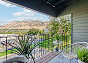 Thumbnail 53 of 62 - A balcony with a chair and a table overlooking a parking lot and a mountain at Cliffs at Canyon Ridge, Ogden, UT, 84401