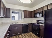 Thumbnail 20 of 47 - A kitchen with dark brown cabinets and black appliances at Del Coronado Apartment , Mesa, 85202