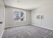 Thumbnail 20 of 44 - A room with a carpeted floor and a window overlooking a house. at Windmill Apartments, Colorado Springs, 80916