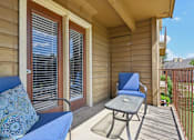 Thumbnail 17 of 39 - A blue couch with a decorative pillow sits on a porch with a small table and chair.