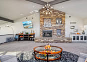 Thumbnail 20 of 37 - A modern living room with a stone fireplace and a television mounted on the wall at Union Heights Apartments, Colorado Springs, Colorado
