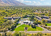 Thumbnail 58 of 62 - A large building complex surrounded by trees and a green lawn at Cliffs at Canyon Ridge, Ogden, UT, 84401