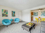 Thumbnail 3 of 45 - A living room with a grey sofa, a blue chair, a yellow chair, and a table with a bowl of fruit on it at Spyglass Creek, Denver, 80224