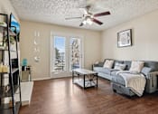 Thumbnail 3 of 39 - A living room with a grey couch and a ceiling fan.