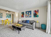 Thumbnail 2 of 45 - A living room with a grey couch, a yellow dining table, and a painting on the wall at Spyglass Creek, Denver, 80224