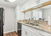 Thumbnail 34 of 51 - a kitchen with white cabinets and granite counter tops and a black refrigerator at The Glen at Highpoint, Dallas, 75243