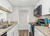 Thumbnail 23 of 51 - a kitchen with white cabinets and granite counter tops and a black microwave at The Glen at Highpoint, Dallas, 75243
