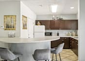 Thumbnail 20 of 35 - A kitchen with a white counter and brown cabinets. at Sarasota South Apartments, Bradenton, Florida