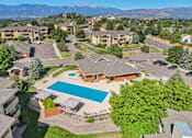 Thumbnail 29 of 41 - A large apartment complex with a swimming pool and a view of mountains in the background.