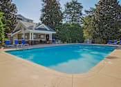 Thumbnail 31 of 32 - A large swimming pool in front of a house with a covered patio. at Cedar Springs Apartments, Raleigh