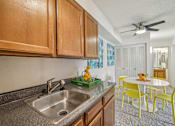Thumbnail 4 of 45 - A kitchen with a sink and yellow chairs at Spyglass Creek, Denver, 80224