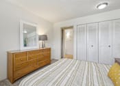 Thumbnail 9 of 45 - A bedroom with a wooden dresser and a striped bedspread at Spyglass Creek, Denver, 80224