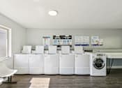 Thumbnail 24 of 35 - A row of white washing machines are lined up in a room. at Sarasota South Apartments, Florida