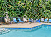 Thumbnail 49 of 64 - A pool surrounded by trees and chairs.at Lofts of Wilmington, Wilmington, North Carolina