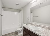 Thumbnail 67 of 105 - A white bathroom with a toilet, sink, and mirror at Sweetwater At Metro North Apartments, Phoenix, Arizona