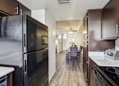 Thumbnail 9 of 47 - A kitchen with a black refrigerator and brown cabinets at Del Coronado Apartment , Arizona, 85202