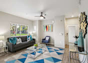 Thumbnail 9 of 105 - A living room with a grey couch, a blue chair, and a glass coffee table at Sweetwater At Metro North Apartments, Phoenix, AZ
