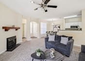 Thumbnail 2 of 32 - A living room with a grey couch, a black fireplace, and a ceiling fan. at Cedar Springs Apartments, Raleigh