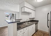 Thumbnail 5 of 44 - A kitchen with white cabinets and a black countertop. at Windmill Apartments, Colorado