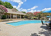 Thumbnail 27 of 39 - A pool surrounded by chairs and a house with a stone wall.