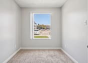 Thumbnail 7 of 44 - A room with a carpeted floor and a window showing a street view. at Windmill Apartments, Colorado Springs, 80916