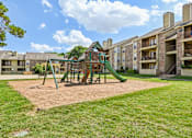 Thumbnail 37 of 39 - A playground with a green slide and sandbox in front of apartment buildings.