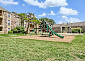 Thumbnail 38 of 39 - A playground with a green slide and a wooden swing set.