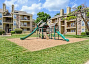 Thumbnail 35 of 39 - A playground with a green slide in front of apartment buildings.