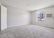 Thumbnail 10 of 44 - A room with a carpeted floor and a window showing a street view. at Windmill Apartments, Colorado Springs, CO